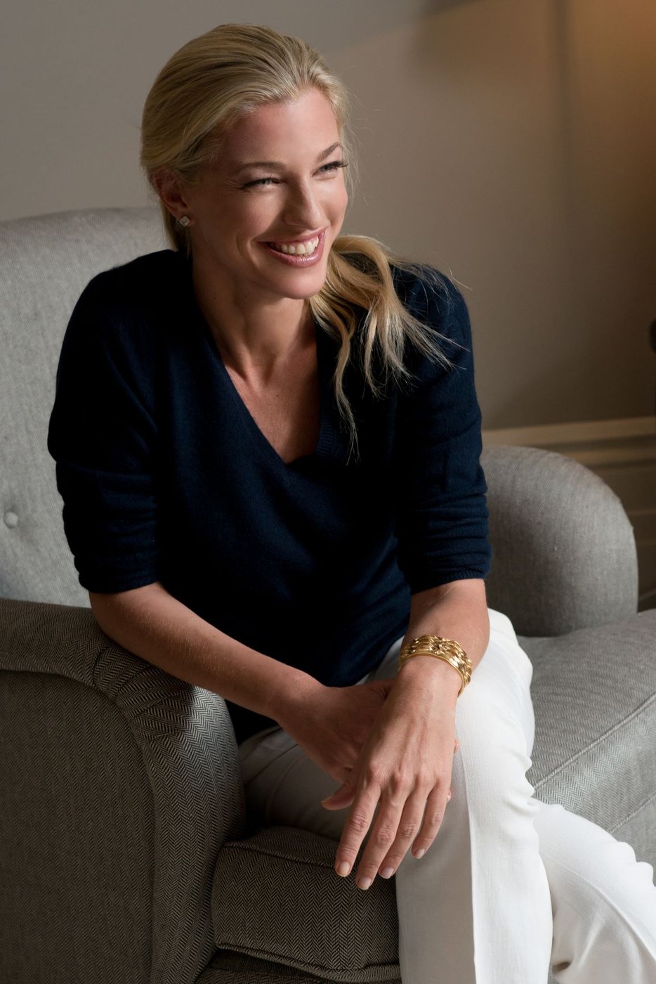 Nicole Junkermann sonríe sentada en un sillón claro, retrato relajado