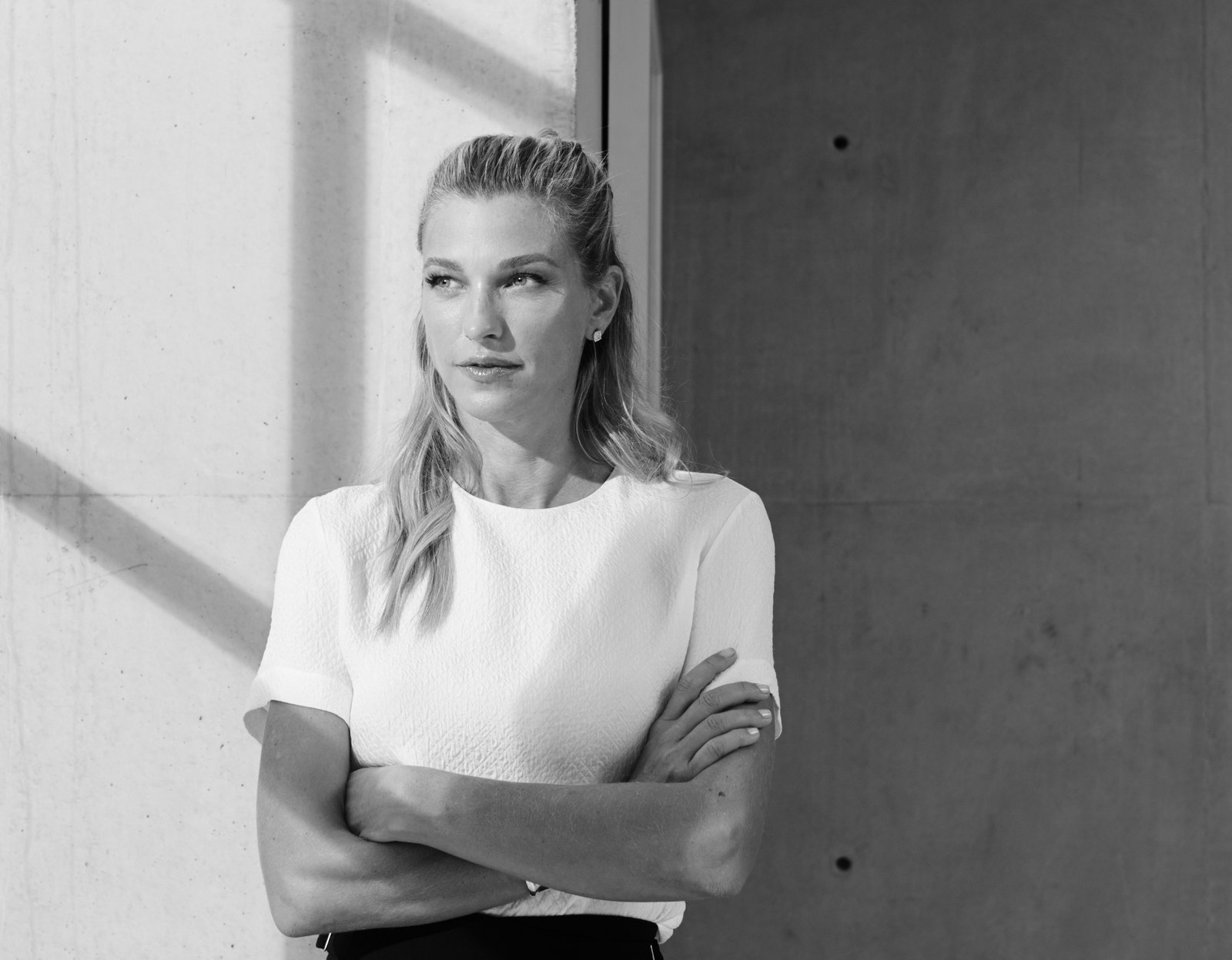 Retrato editorial en blanco y negro de Nicole Junkermann junto a una pared de luz, con la mirada puesta a lo lejos